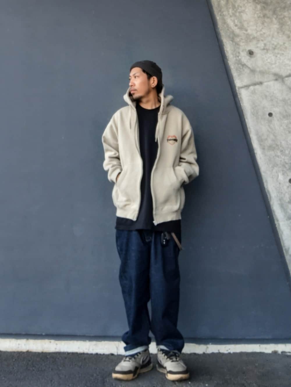 ベージュ系のパーカー、ブラック系のTシャツ/カットソー、ブルー系のデニムパンツを着用したメンズの春コーディネートの2枚目の写真