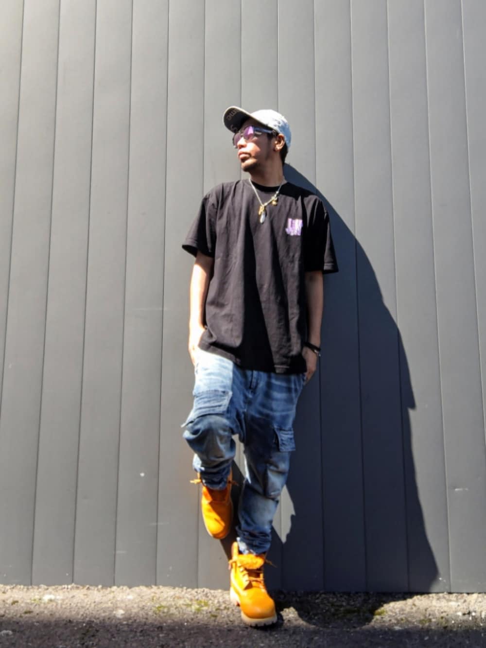 ブラック系のTシャツ/カットソー、ブルー系のデニムパンツ、イエロー系のブーツを着用したメンズの秋コーディネートの2枚目の写真