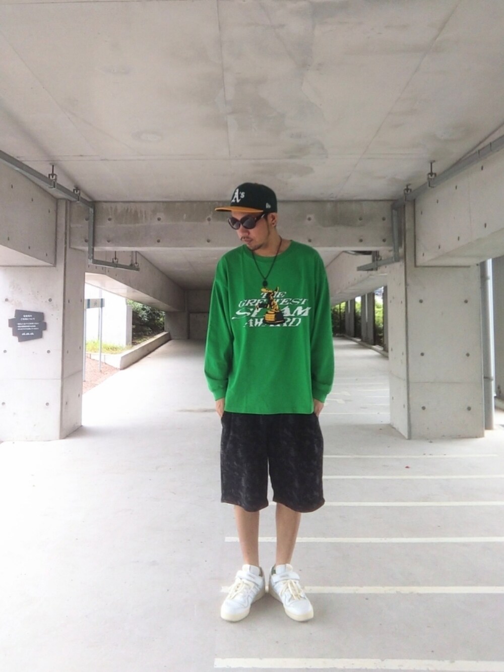 グリーン系のTシャツ/カットソー、ブラック系のパンツ、ホワイト系のスニーカーを着用したメンズの夏コーディネートの2枚目の写真