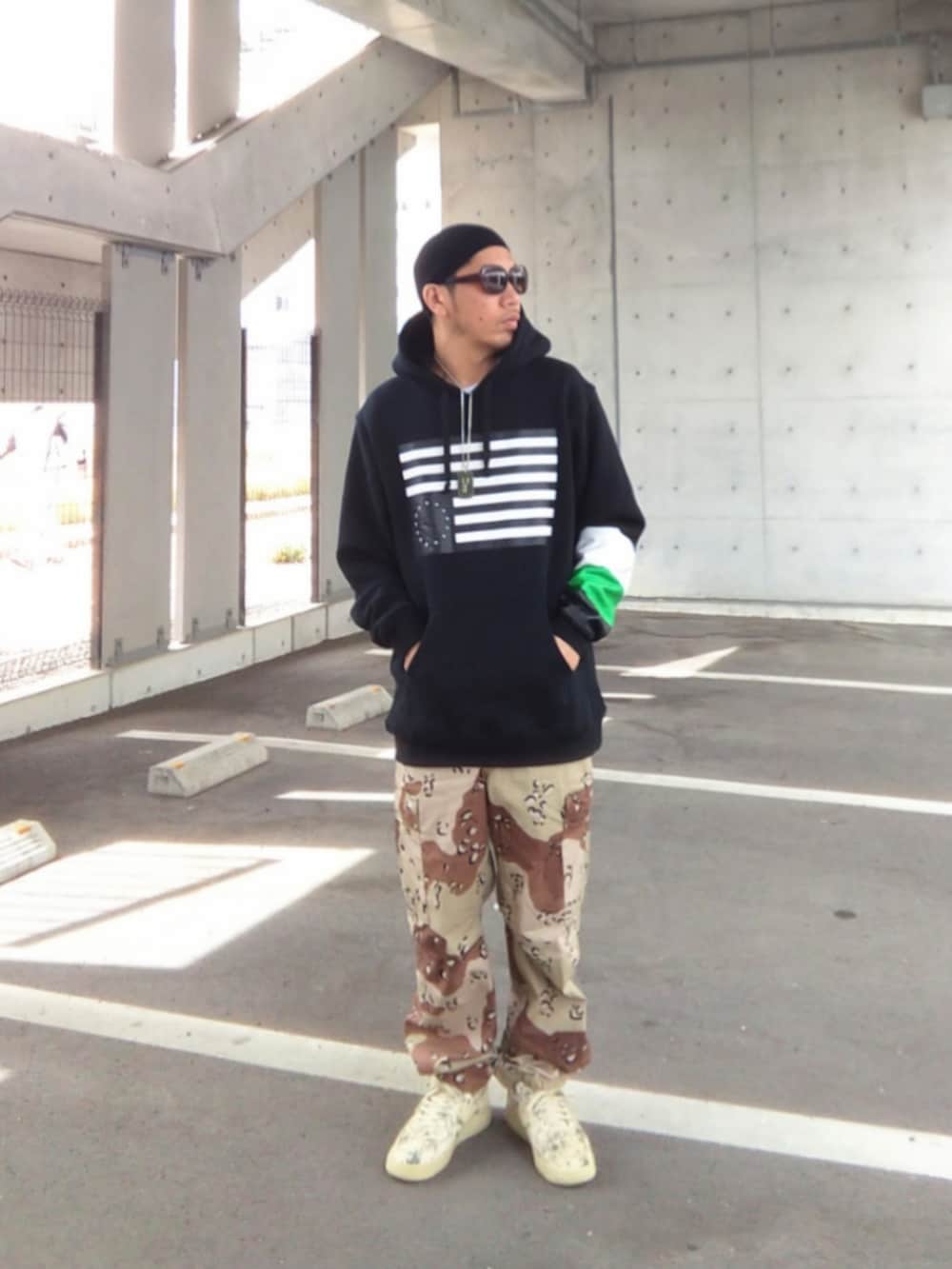 ブラック系のパーカー、その他のカーゴパンツ、ベージュ系のスニーカーを着用したメンズの春コーディネートの2枚目の写真