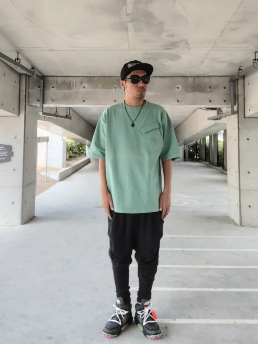 グリーン系のTシャツ/カットソー、ブラック系のその他パンツ、ブラック系のスニーカーを着用したメンズの夏コーディネートの2枚目の写真