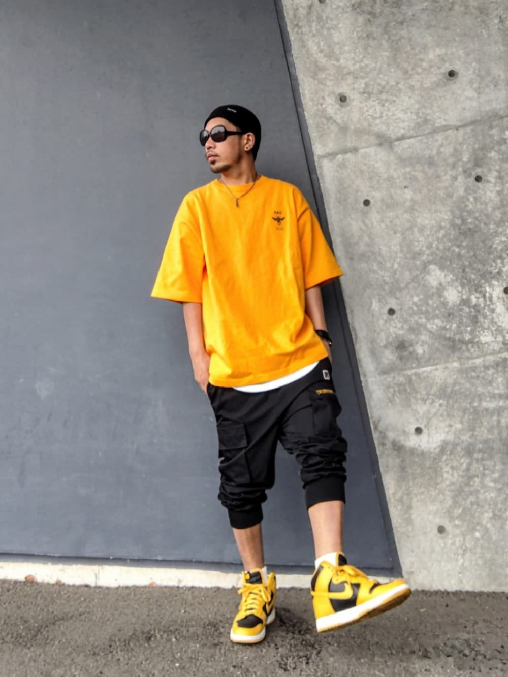 イエロー系のTシャツ/カットソー、ブラック系のカーゴパンツ、イエロー系のスニーカーを着用したメンズの夏コーディネートの2枚目の写真
