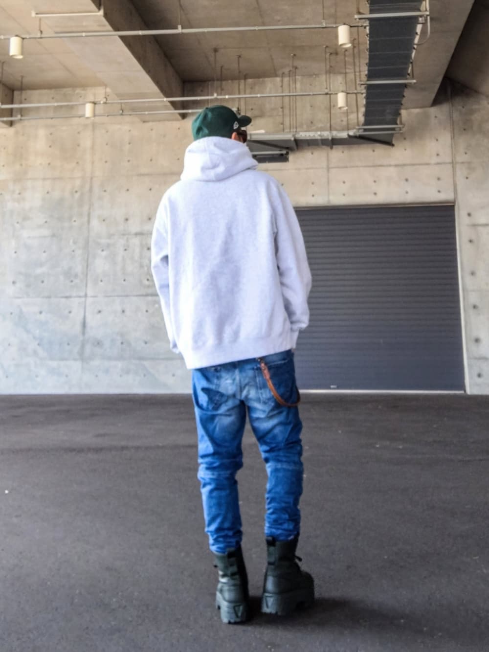 グレー系のパーカー、ブルー系のデニムパンツ、グリーン系のスニーカーを着用したメンズの冬コーディネートの3枚目の写真