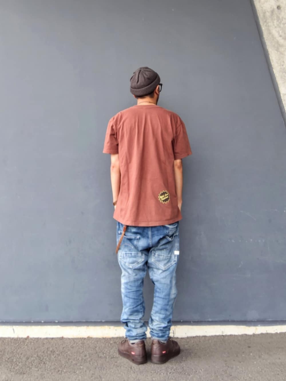 ブラウン系のTシャツ/カットソー、ブルー系のデニムパンツ、ブラウン系のスニーカーを着用したメンズの夏コーディネートの2枚目の写真