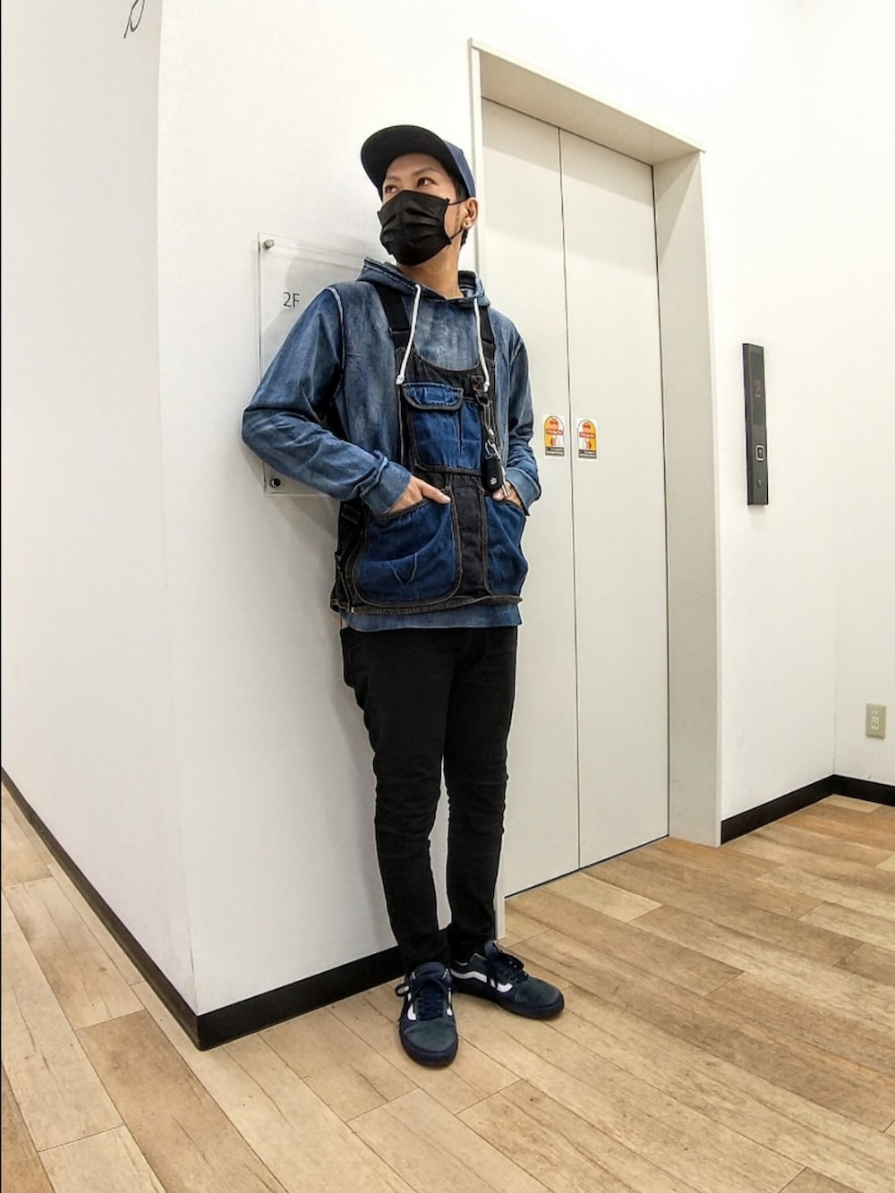 ブルー系のベスト、ブルー系のパーカー、ブラック系のデニムパンツを着用したメンズの秋コーディネートの3枚目の写真