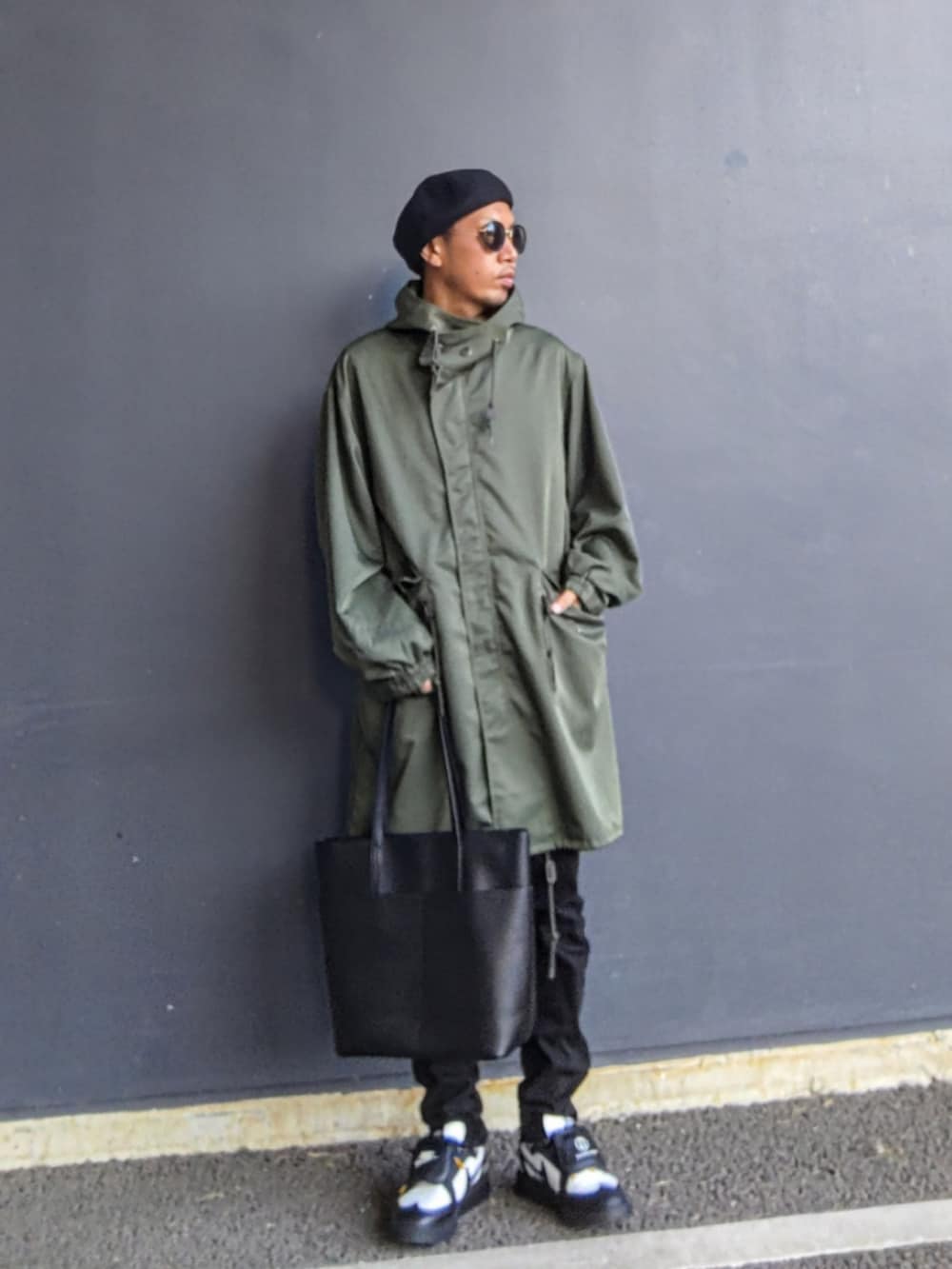 グリーン系のモッズコート、ブラック系のチノパンツ、ブラック系のスニーカーを着用したメンズの秋コーディネートの2枚目の写真