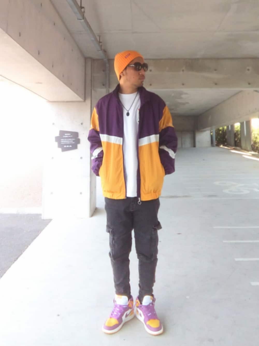 パープル系のナイロンジャケット、ブラック系のデニムパンツ、イエロー系のスニーカーを着用したメンズの春コーディネートの2枚目の写真