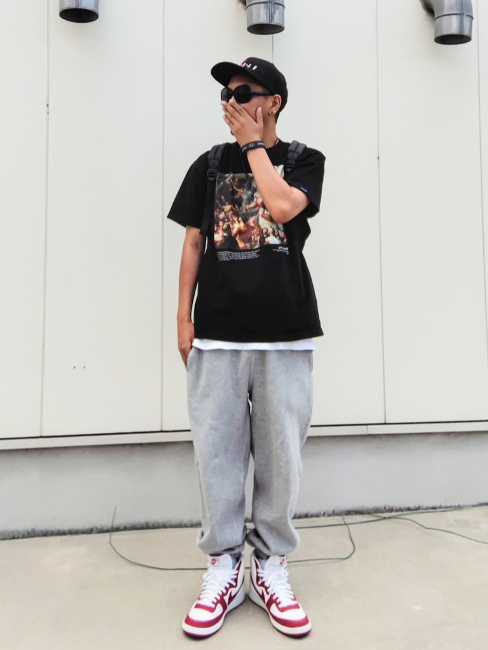 ブラック系のTシャツ/カットソー、ブラック系のバックパック/リュック、グレー系のスウェットパンツを着用したメンズの秋コーディネートの2枚目の写真