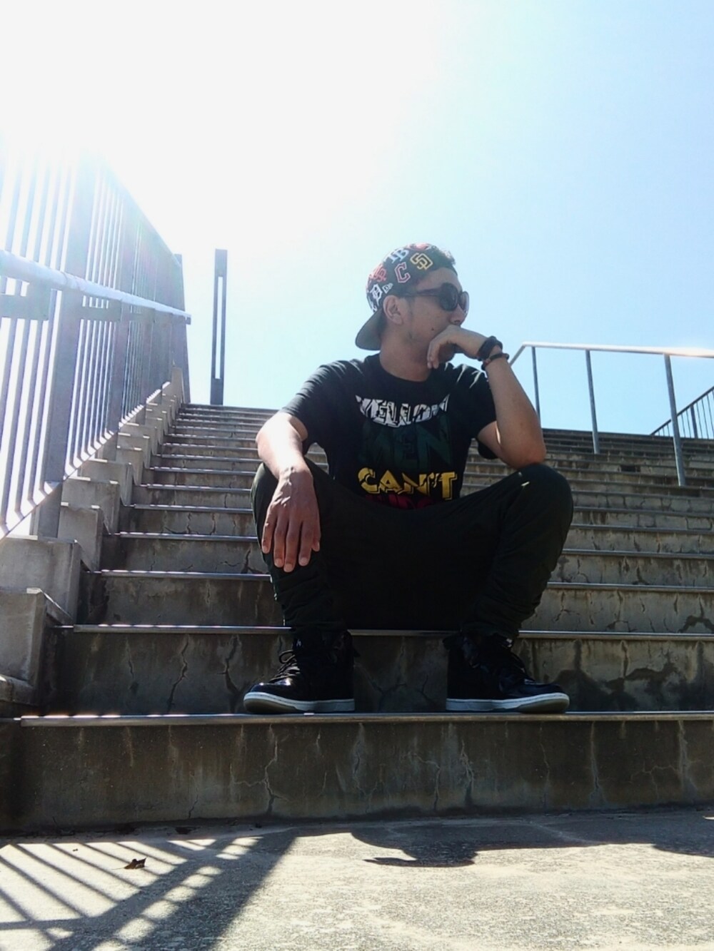 ブラック系のTシャツ/カットソー、グリーン系のパンツ、ブラック系のスニーカーを着用したメンズの夏コーディネートの2枚目の写真