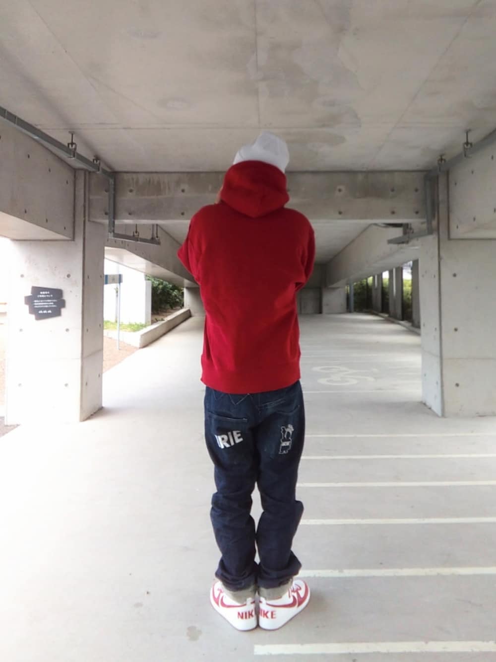 レッド系のパーカー、ブルー系のデニムパンツ、ホワイト系のスニーカーを着用したメンズの冬コーディネートの3枚目の写真