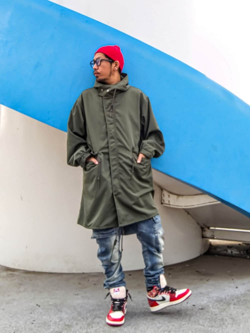 グリーン系のモッズコート、ブルー系のデニムパンツ、レッド系のスニーカーを着用したメンズの冬コーディネートの3枚目の写真