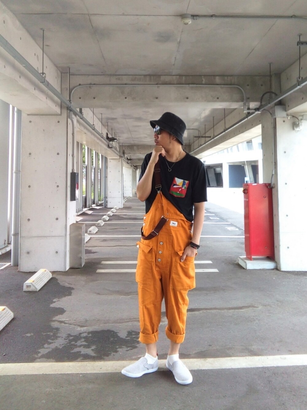 ブラック系のTシャツ/カットソー、オレンジ系のサロペット/オーバーオール、グレー系のスニーカーを着用したメンズの夏コーディネートの2枚目の写真