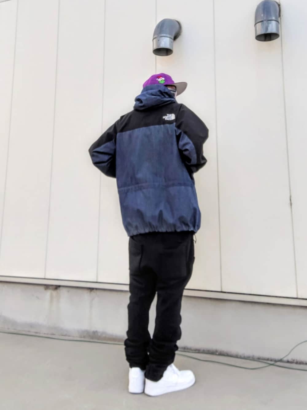 ブルー系のナイロンジャケット、ブラック系のその他パンツ、ホワイト系のスニーカーを着用したメンズの冬コーディネートの3枚目の写真