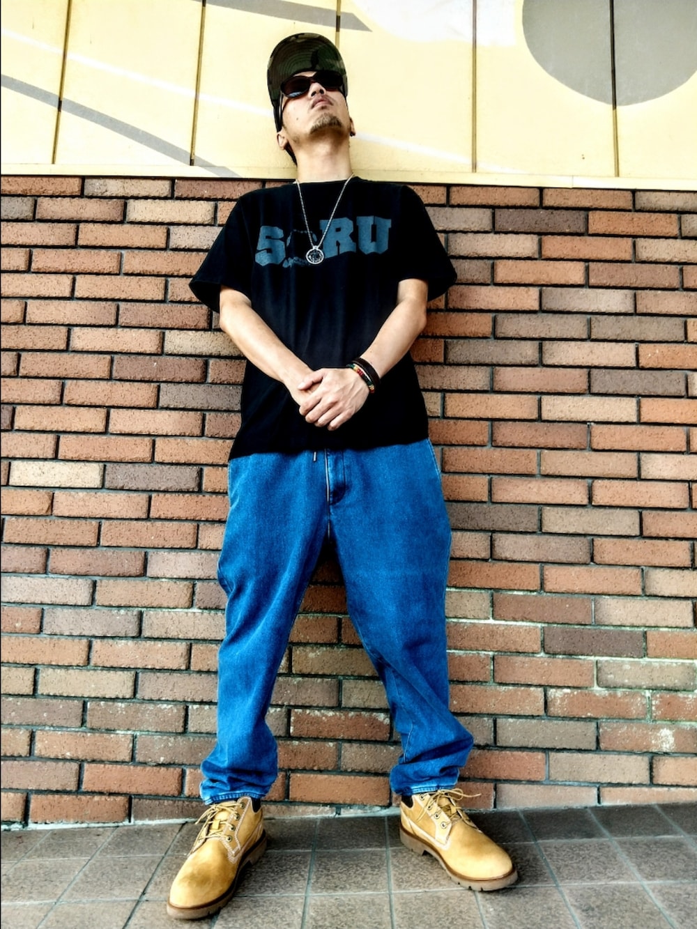 ブラック系のTシャツ/カットソー、ブルー系のデニムパンツ、イエロー系のブーツを着用したメンズの夏コーディネートの2枚目の写真