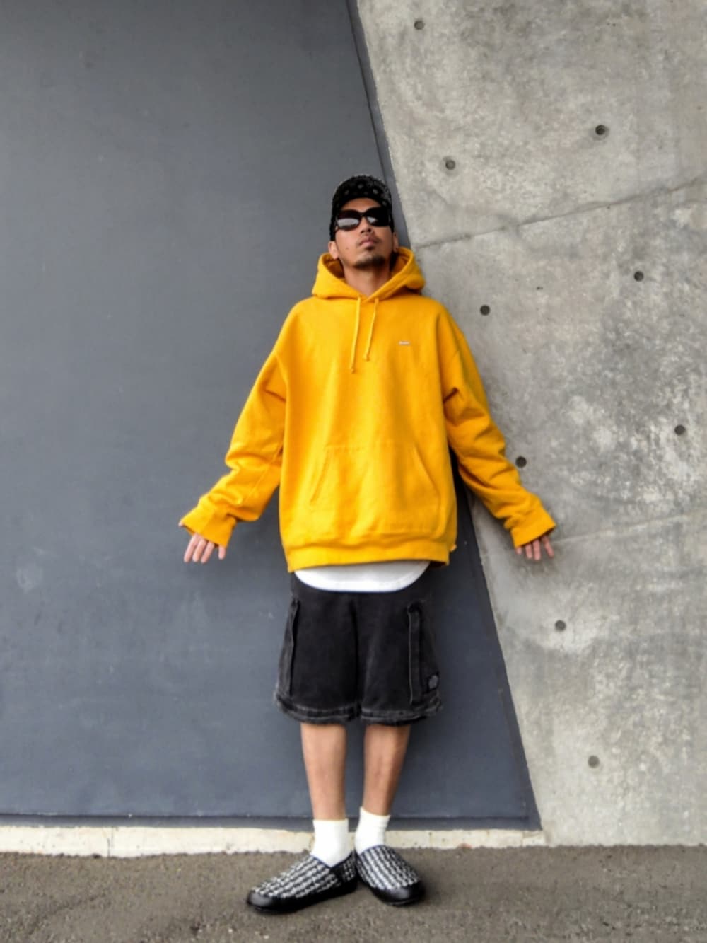 イエロー系のパーカー、ホワイト系のタンクトップ、ブラック系のその他パンツを着用したメンズの春コーディネートの2枚目の写真