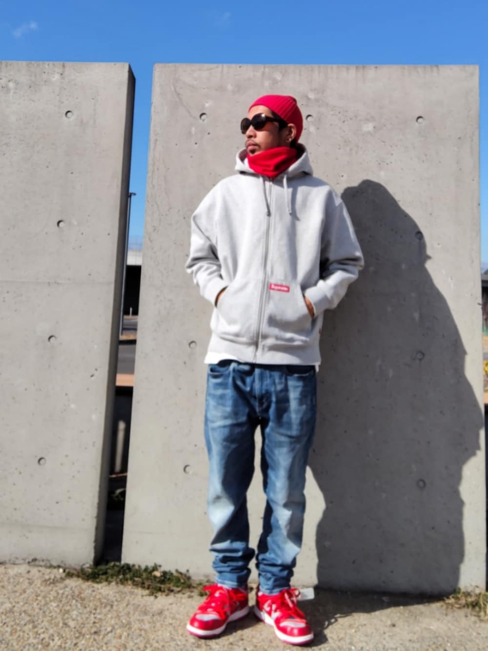 グレー系のパーカー、ブルー系のデニムパンツ、レッド系のスニーカーを着用したメンズの冬コーディネートの2枚目の写真