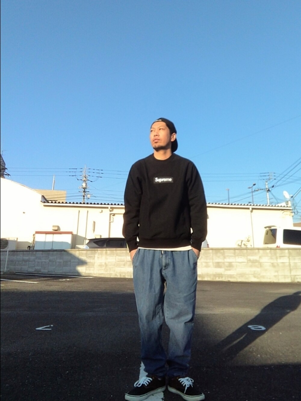 ブラック系のスウェット、ブルー系のデニムパンツ、ブラック系のスニーカーを着用したメンズの冬コーディネートの3枚目の写真