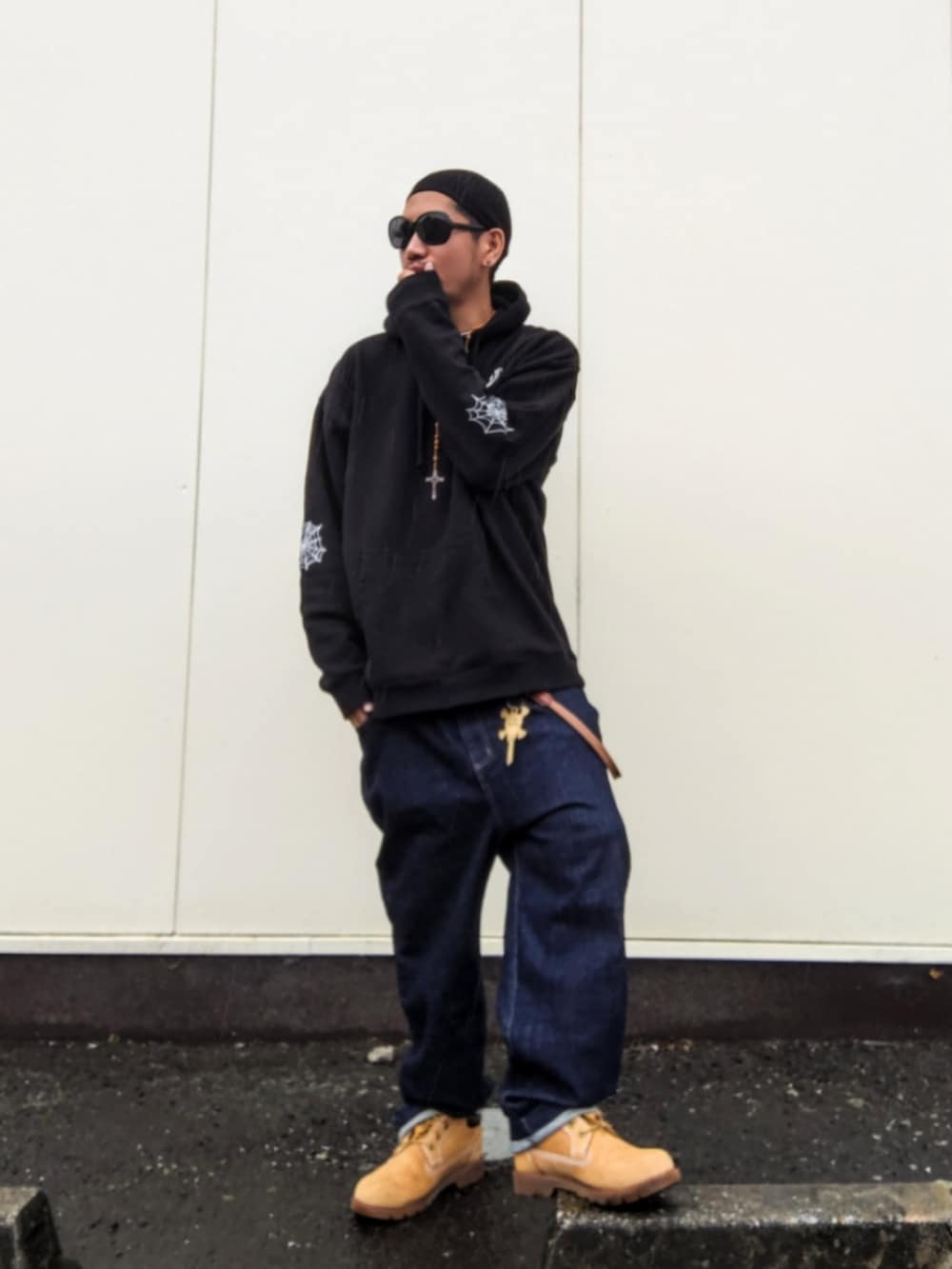 ブラック系のパーカー、ブルー系のデニムパンツ、イエロー系のブーツを着用したメンズの春コーディネートの2枚目の写真