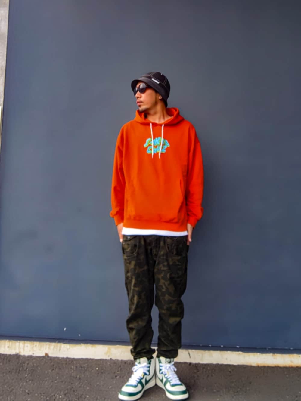 オレンジ系のパーカー、その他のパンツ、ホワイト系のスニーカーを着用したメンズの秋コーディネートの2枚目の写真