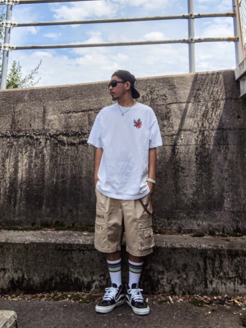 ホワイト系のTシャツ/カットソー、ベージュ系のカーゴパンツ、ブラック系のスニーカーを着用したメンズの夏コーディネートの2枚目の写真