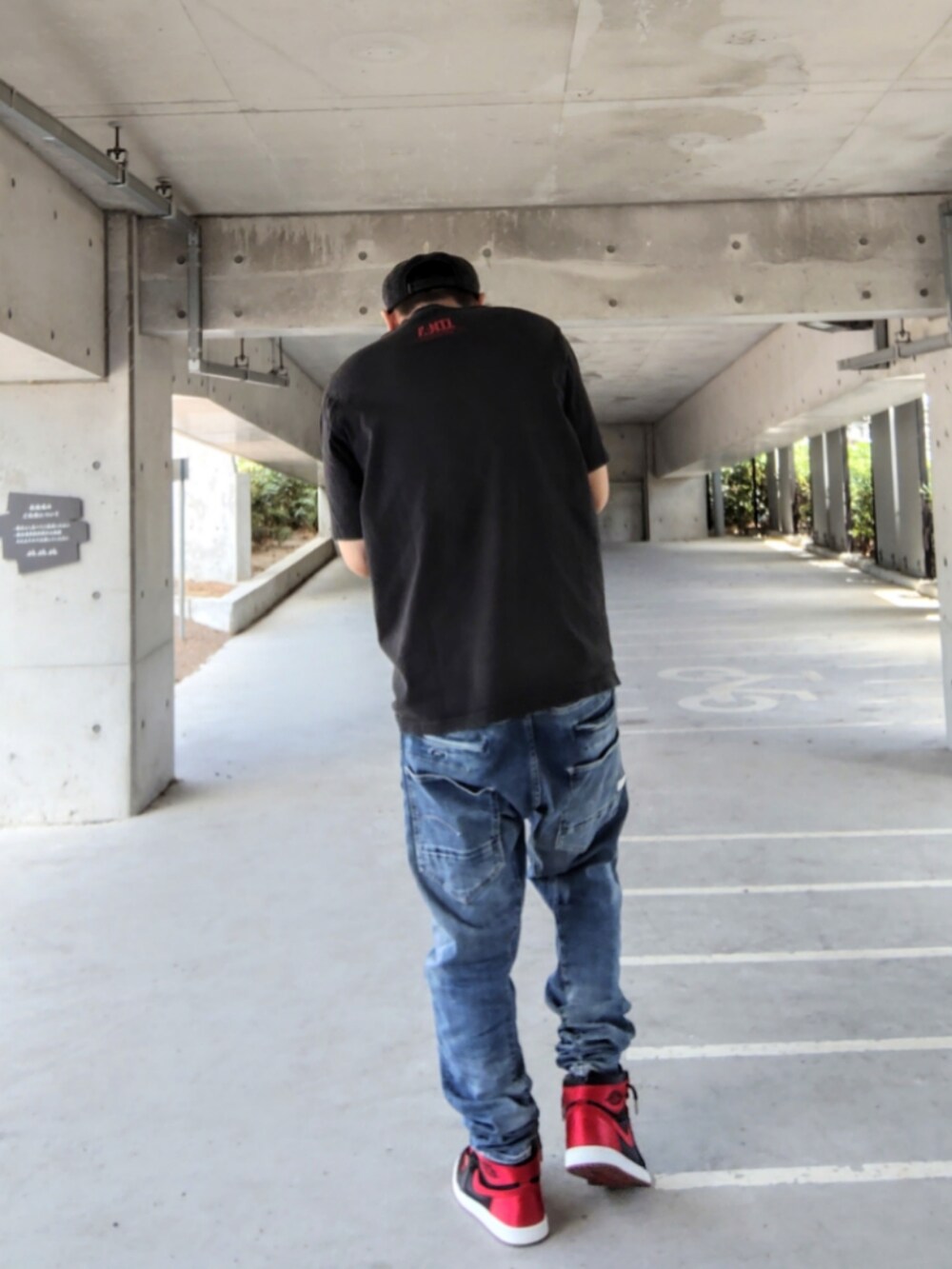 ブラック系のTシャツ/カットソー、ブラック系のスニーカー、ブルー系のデニムパンツを着用したメンズの夏コーディネートの2枚目の写真