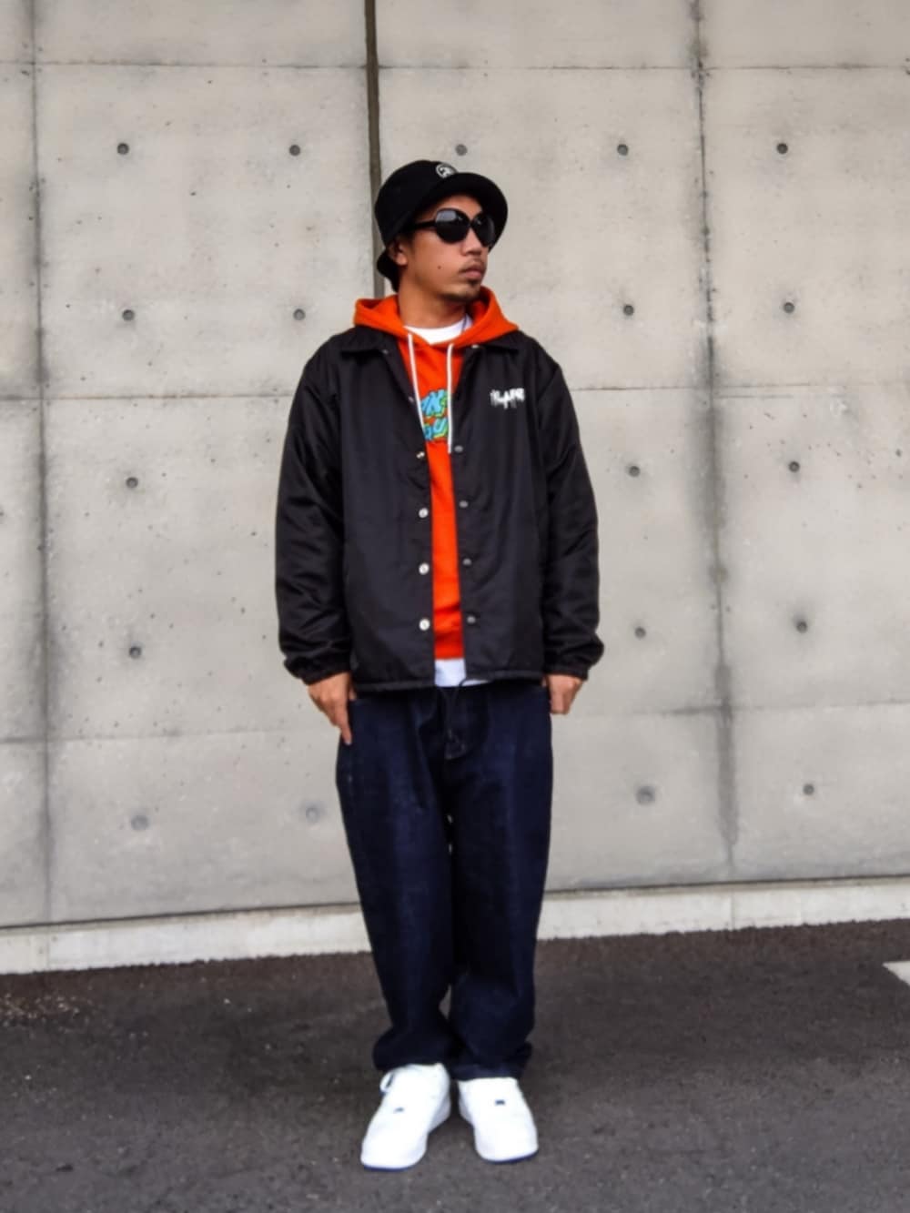 ブラック系のナイロンジャケット、オレンジ系のパーカー、ホワイト系のTシャツ/カットソーを着用したメンズの秋コーディネートの2枚目の写真