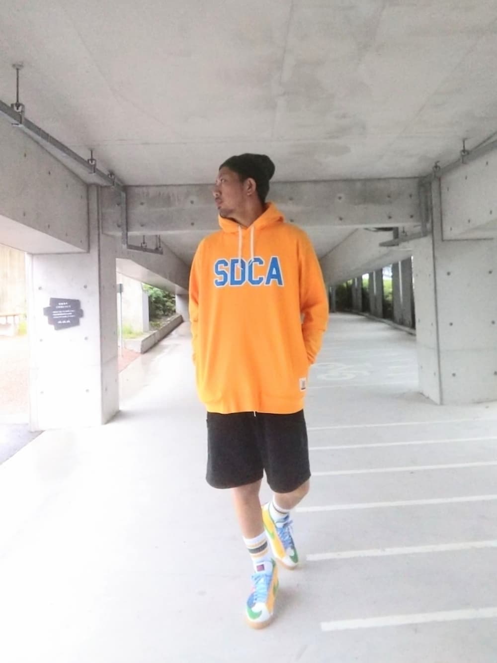 イエロー系のパーカー、ブラック系のその他パンツ、オレンジ系のスニーカーを着用したメンズの秋コーディネートの3枚目の写真