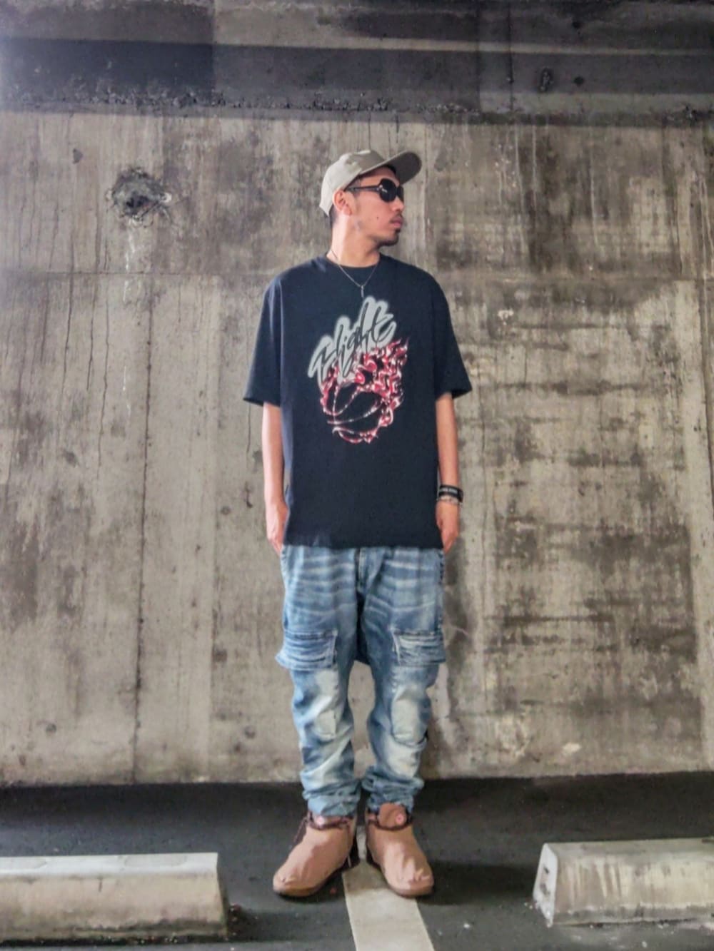 ブラック系のTシャツ/カットソー、ブルー系のデニムパンツ、ブラウン系のスニーカーを着用したメンズの夏コーディネートの2枚目の写真