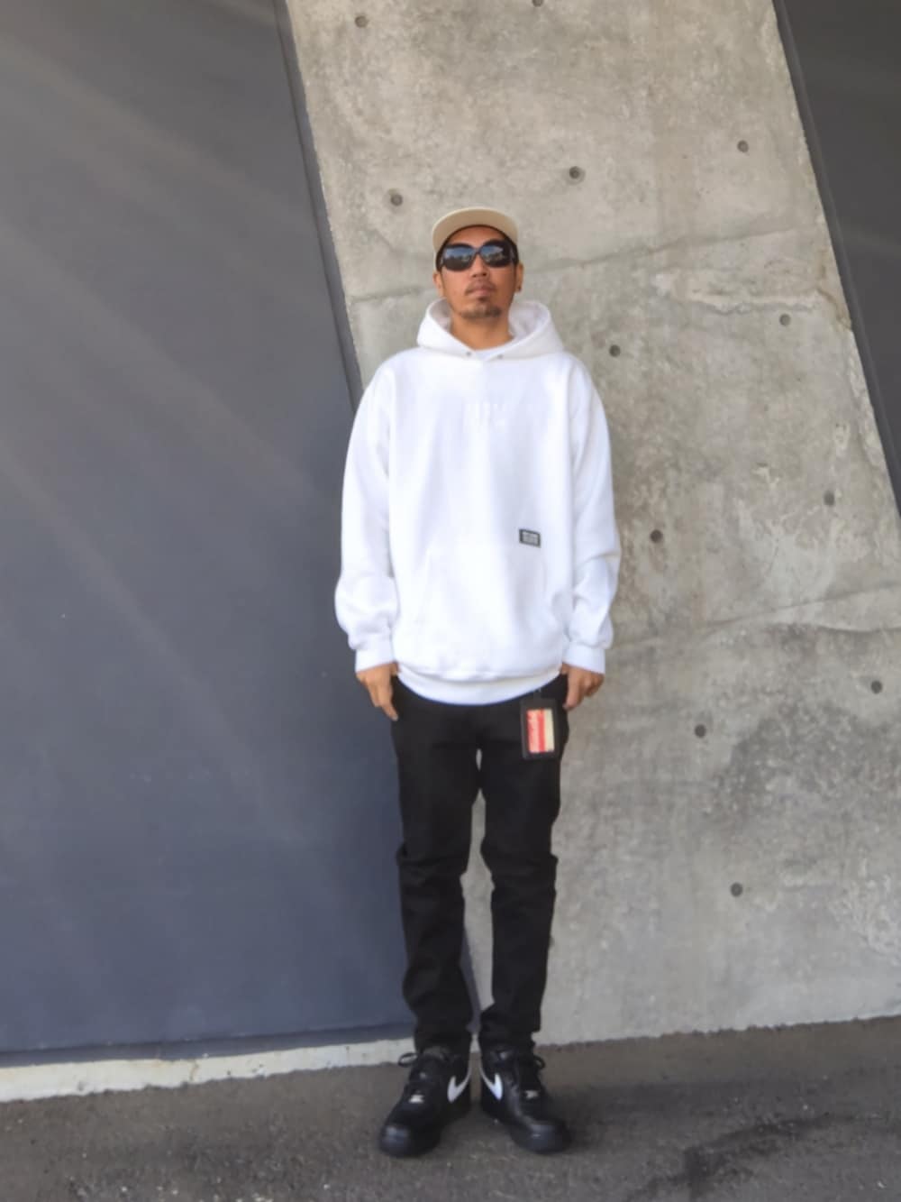 ホワイト系のパーカー、ブラック系のデニムパンツ、ブラック系のスニーカーを着用したメンズの冬コーディネートの2枚目の写真
