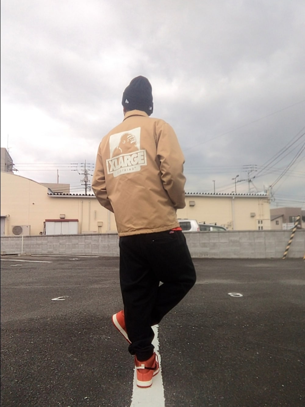 ベージュ系のナイロンジャケット、オレンジ系のTシャツ/カットソー、ブラック系のスウェットパンツを着用したメンズの冬コーディネートの2枚目の写真