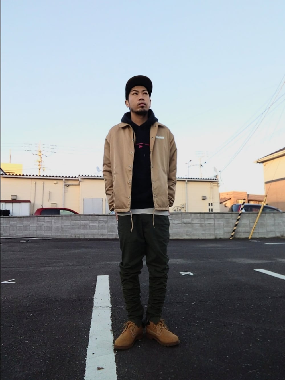 ベージュ系のナイロンジャケット、ブラック系のパーカー、グリーン系のパンツを着用したメンズの冬コーディネートの3枚目の写真