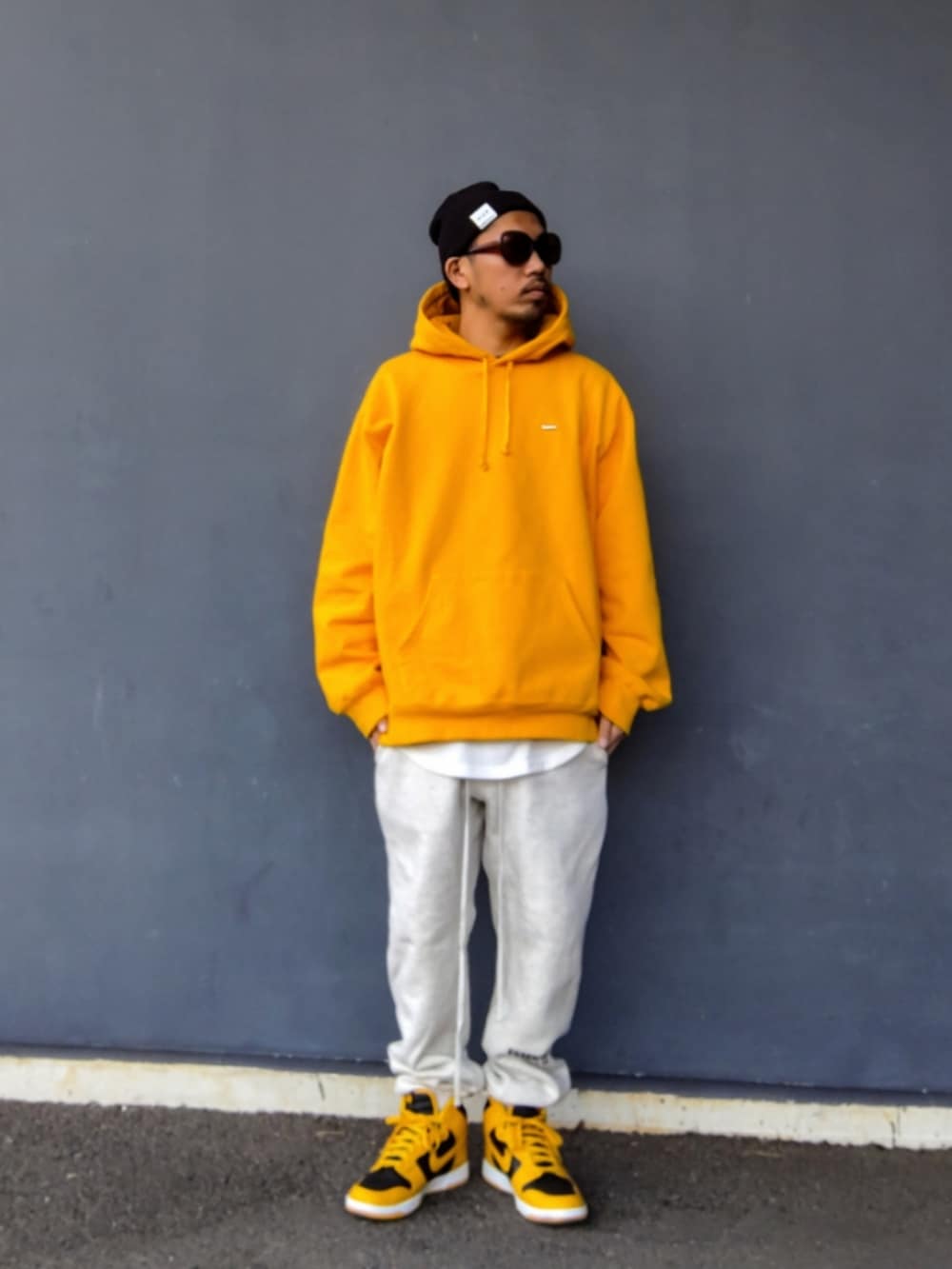 イエロー系のパーカー、ホワイト系のタンクトップ、グレー系のスウェットパンツを着用したメンズの冬コーディネートの2枚目の写真