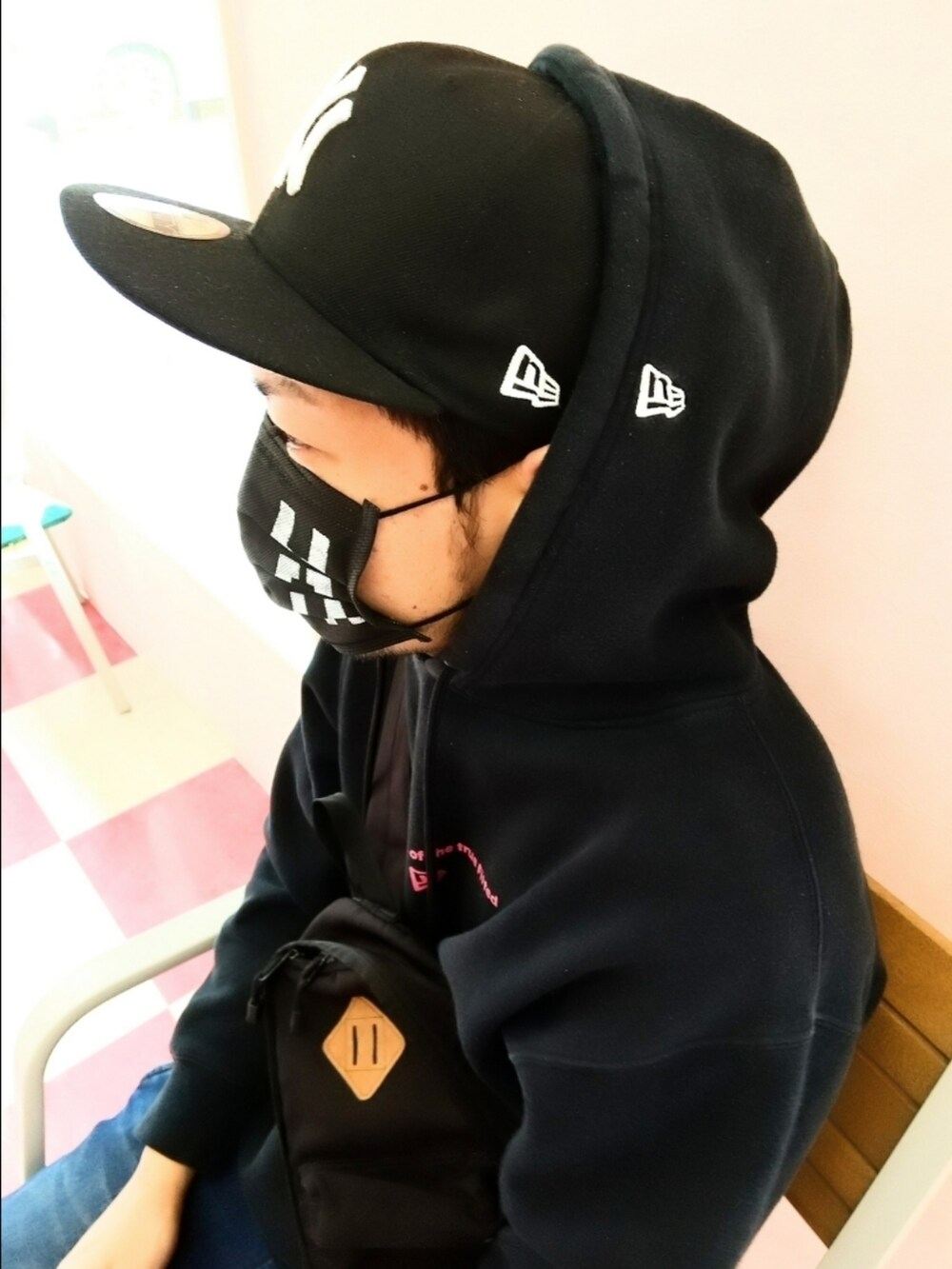 ブラック系のパーカー、ブラック系のボディバッグ/ウエストポーチ、ブルー系のパンツを着用したメンズの春コーディネートの3枚目の写真