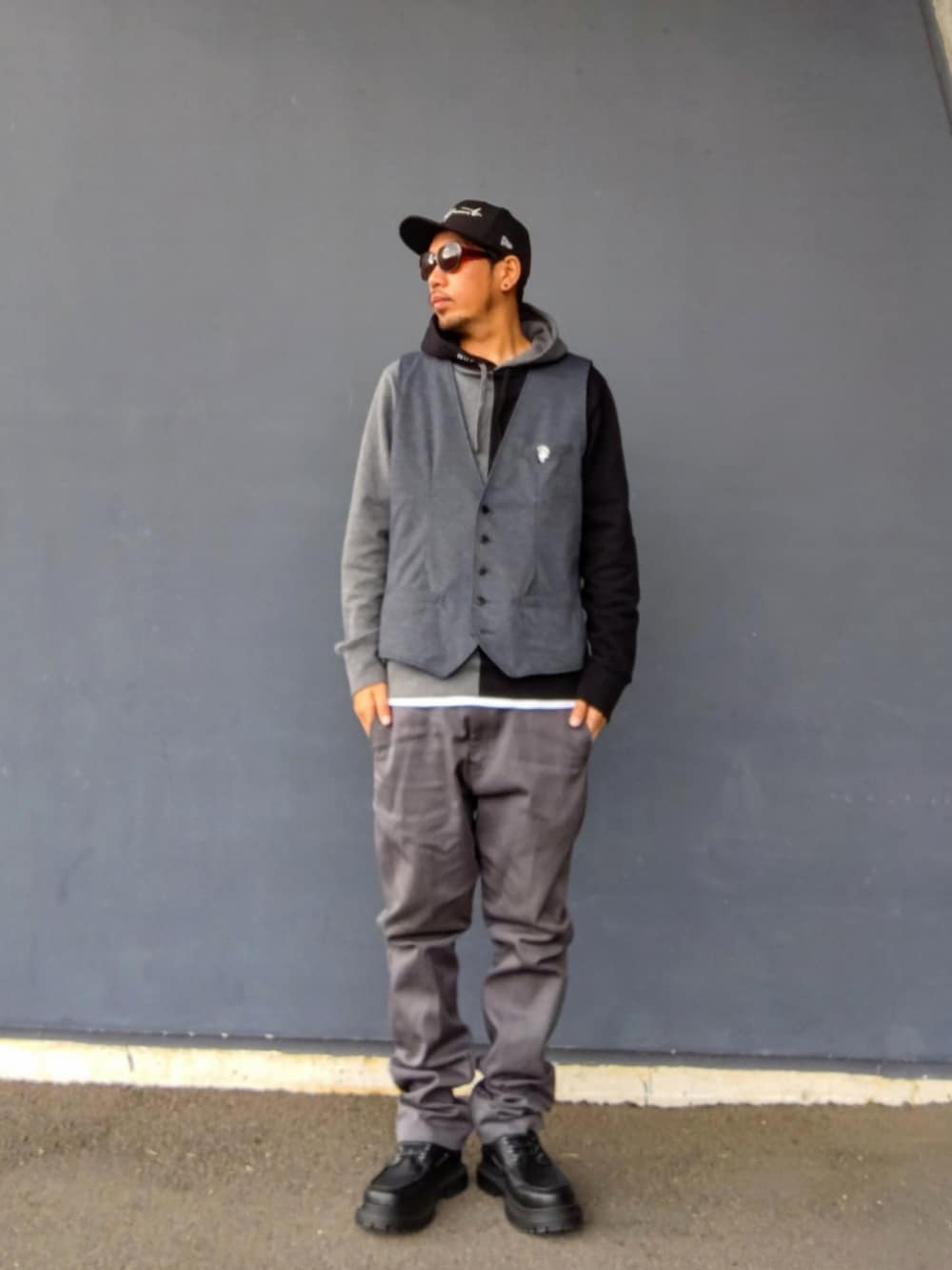 グレー系のベスト、ブラック系のパーカー、グレー系のチノパンツを着用したメンズの冬コーディネートの3枚目の写真