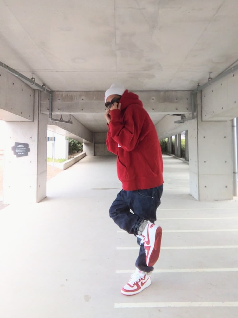 レッド系のパーカー、ブルー系のデニムパンツ、ホワイト系のスニーカーを着用したメンズの冬コーディネートの2枚目の写真