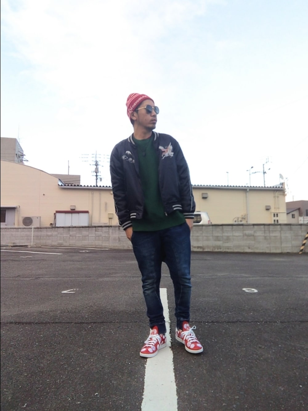 レッド系のスニーカー、ブルー系のパンツ、ブラック系のスカジャンを着用したメンズの冬コーディネートの2枚目の写真