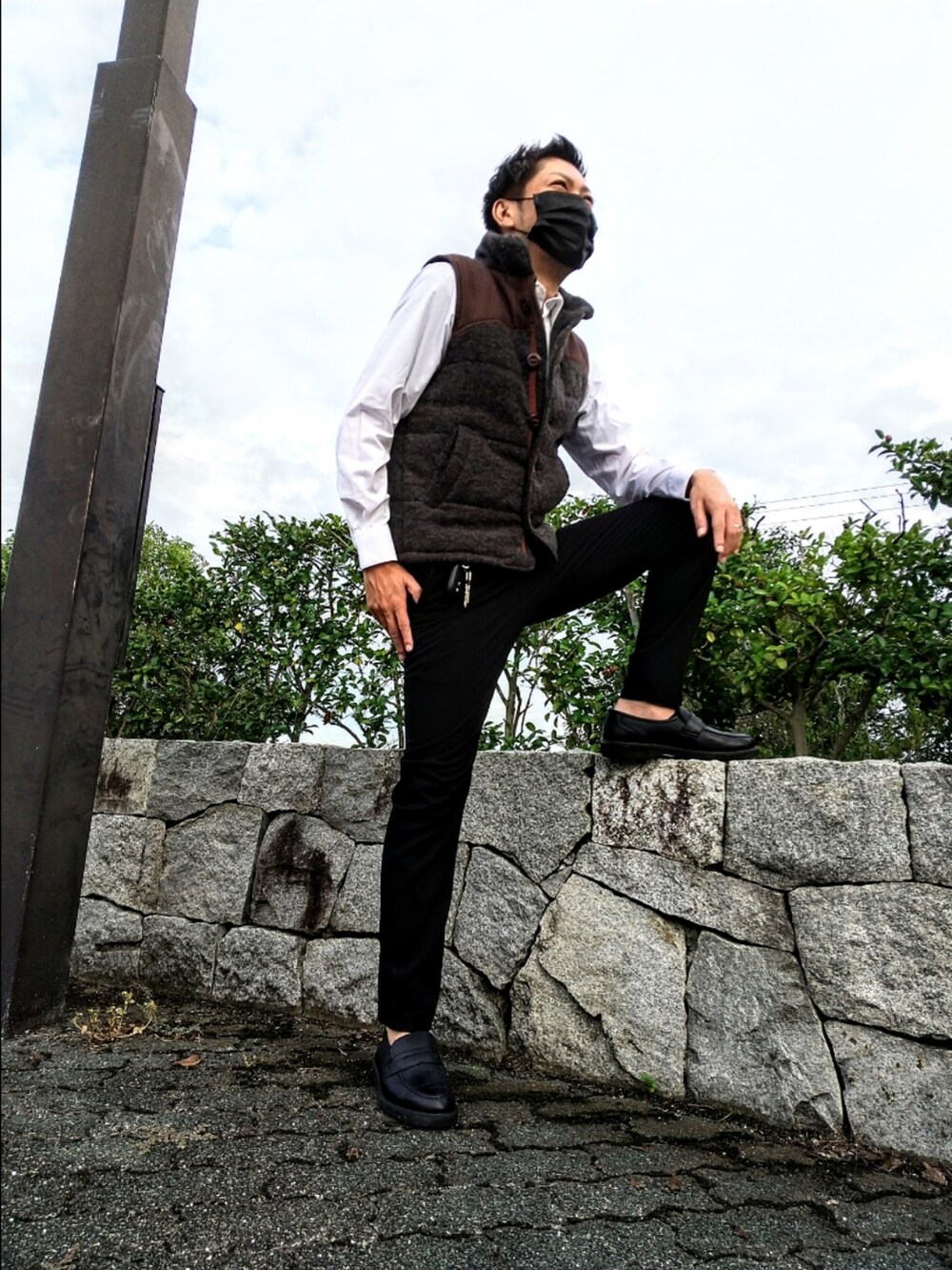 グレー系のベスト、ブラック系のスラックス、ブラック系のローファーを着用したメンズの秋コーディネートの3枚目の写真