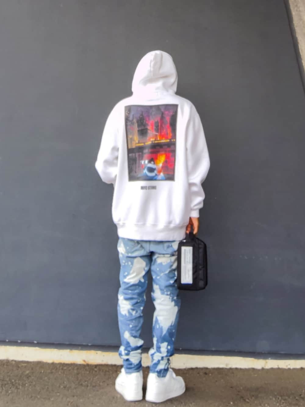 ホワイト系のパーカー、ブラック系のバッグ、ブルー系のデニムパンツを着用したメンズの冬コーディネートの2枚目の写真