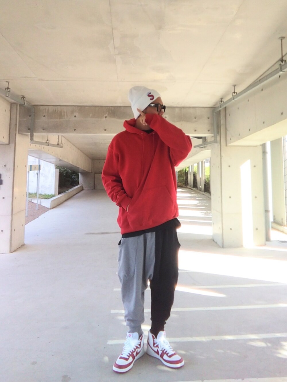 レッド系のパーカー、ブラック系のTシャツ/カットソー、その他のスウェットパンツを着用したメンズの秋コーディネートの5枚目の写真