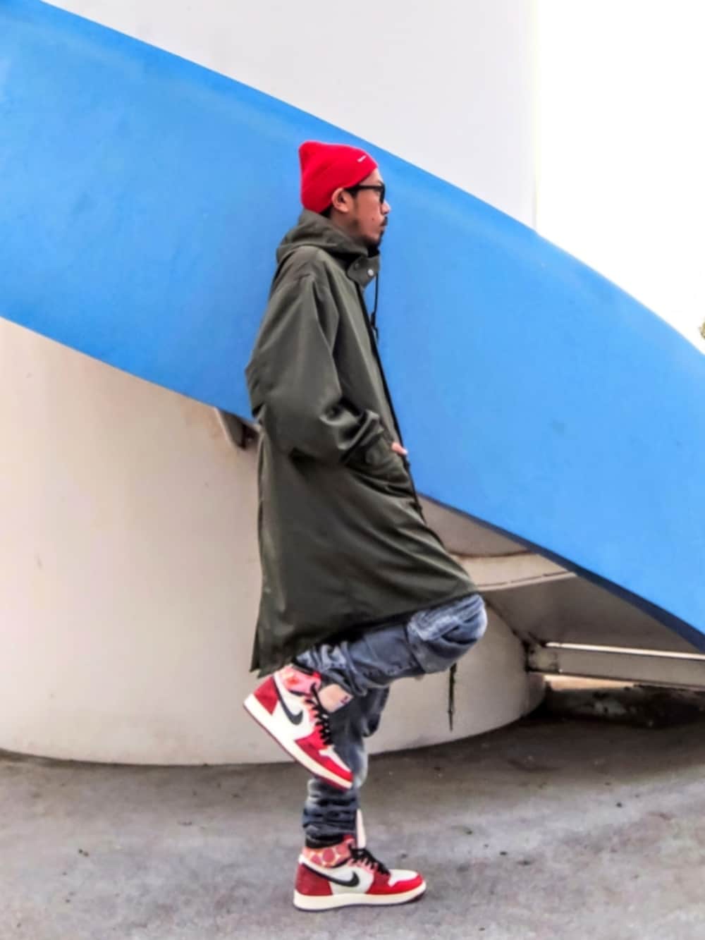 グリーン系のモッズコート、ブルー系のデニムパンツ、レッド系のスニーカーを着用したメンズの冬コーディネートの2枚目の写真