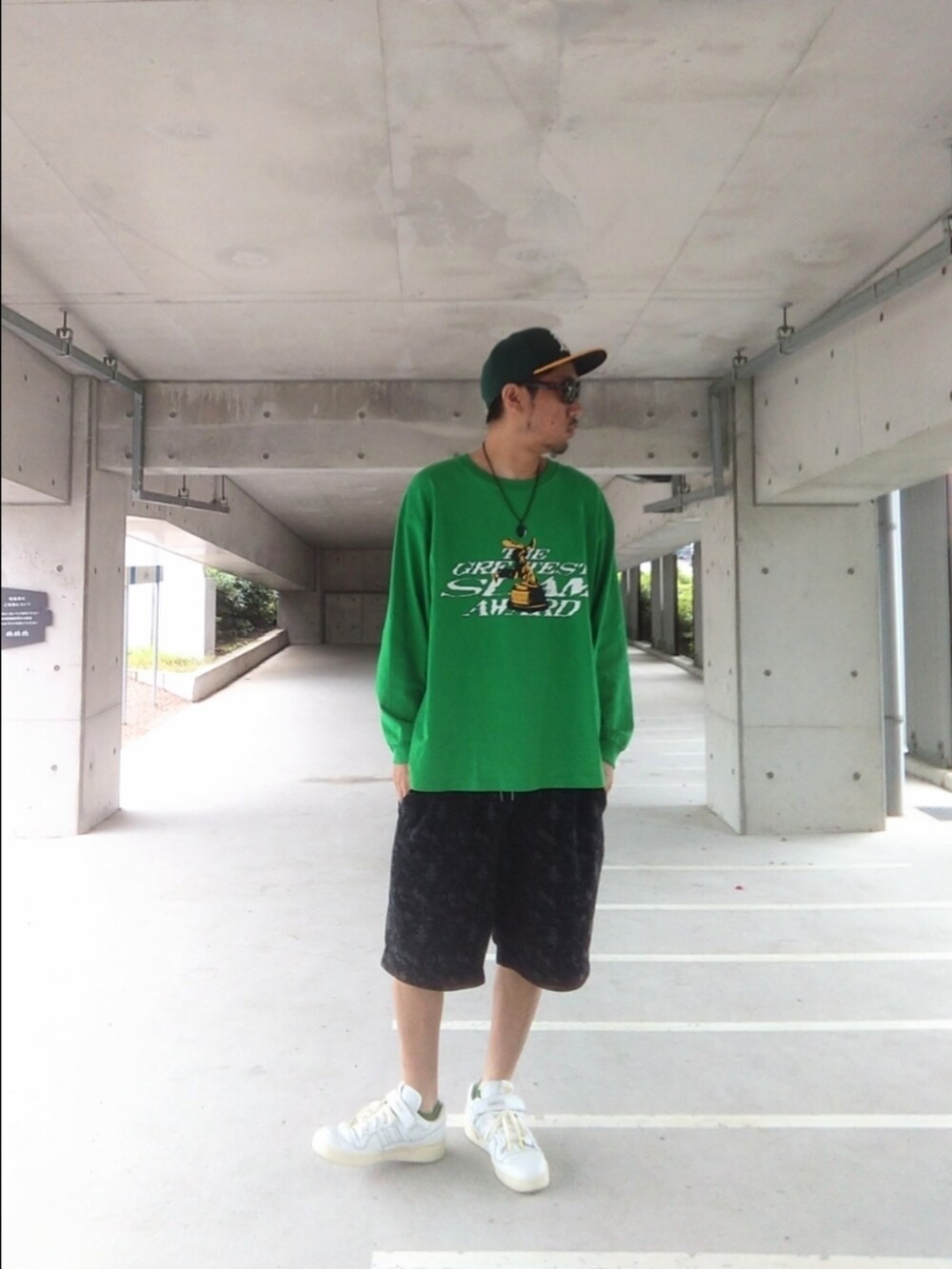 グリーン系のTシャツ/カットソー、ブラック系のパンツ、ホワイト系のスニーカーを着用したメンズの夏コーディネートの3枚目の写真
