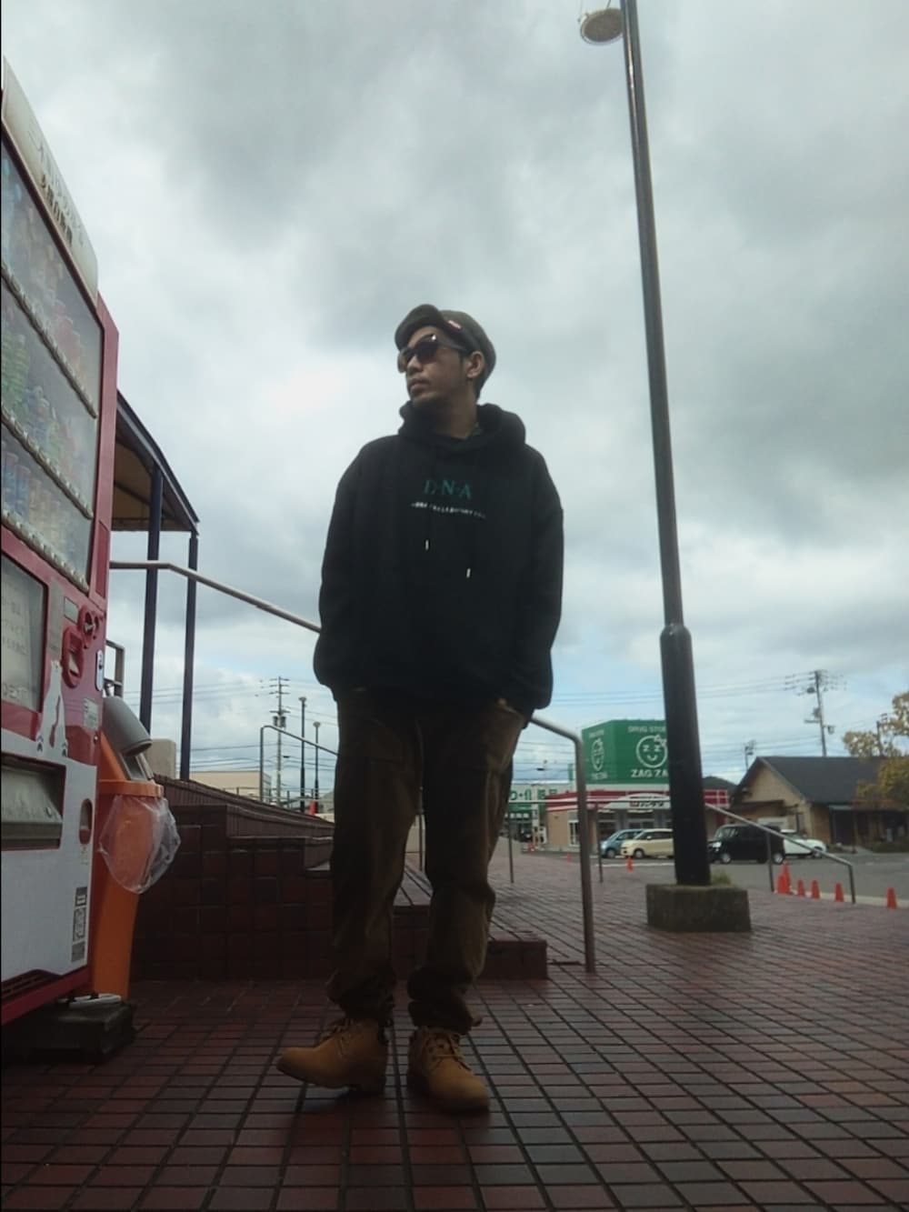 ブラック系のパーカー、ブラウン系のその他パンツ、イエロー系のブーツを着用したメンズの春コーディネートの3枚目の写真