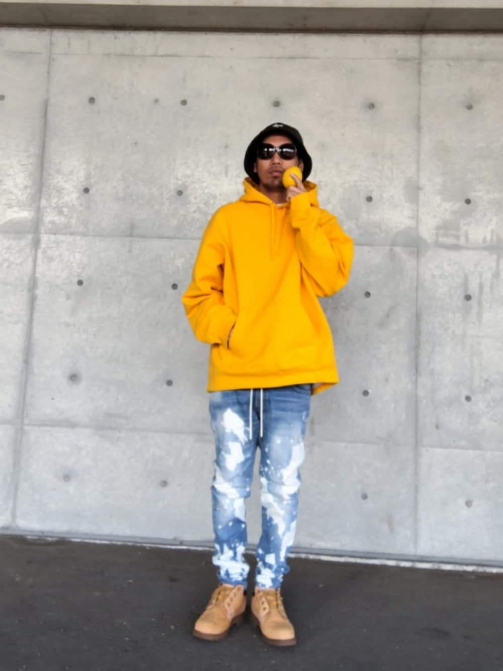 イエロー系のパーカー、ブルー系のデニムパンツ、イエロー系のブーツを着用したメンズの秋コーディネートの2枚目の写真