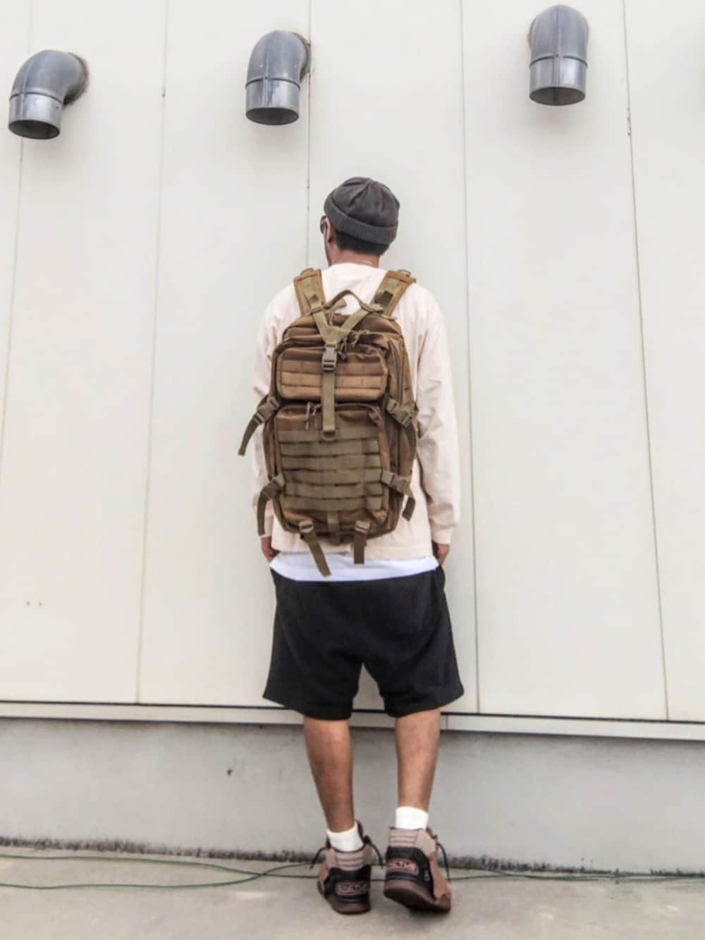 ベージュ系のTシャツ/カットソー、ホワイト系のタンクトップ、グリーン系のバックパック/リュックを着用したメンズの秋コーディネートの2枚目の写真