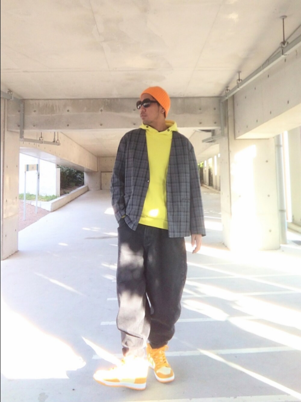 グレー系のノーカラージャケット、イエロー系のパーカー、ブラック系のデニムパンツを着用したメンズの冬コーディネートの3枚目の写真