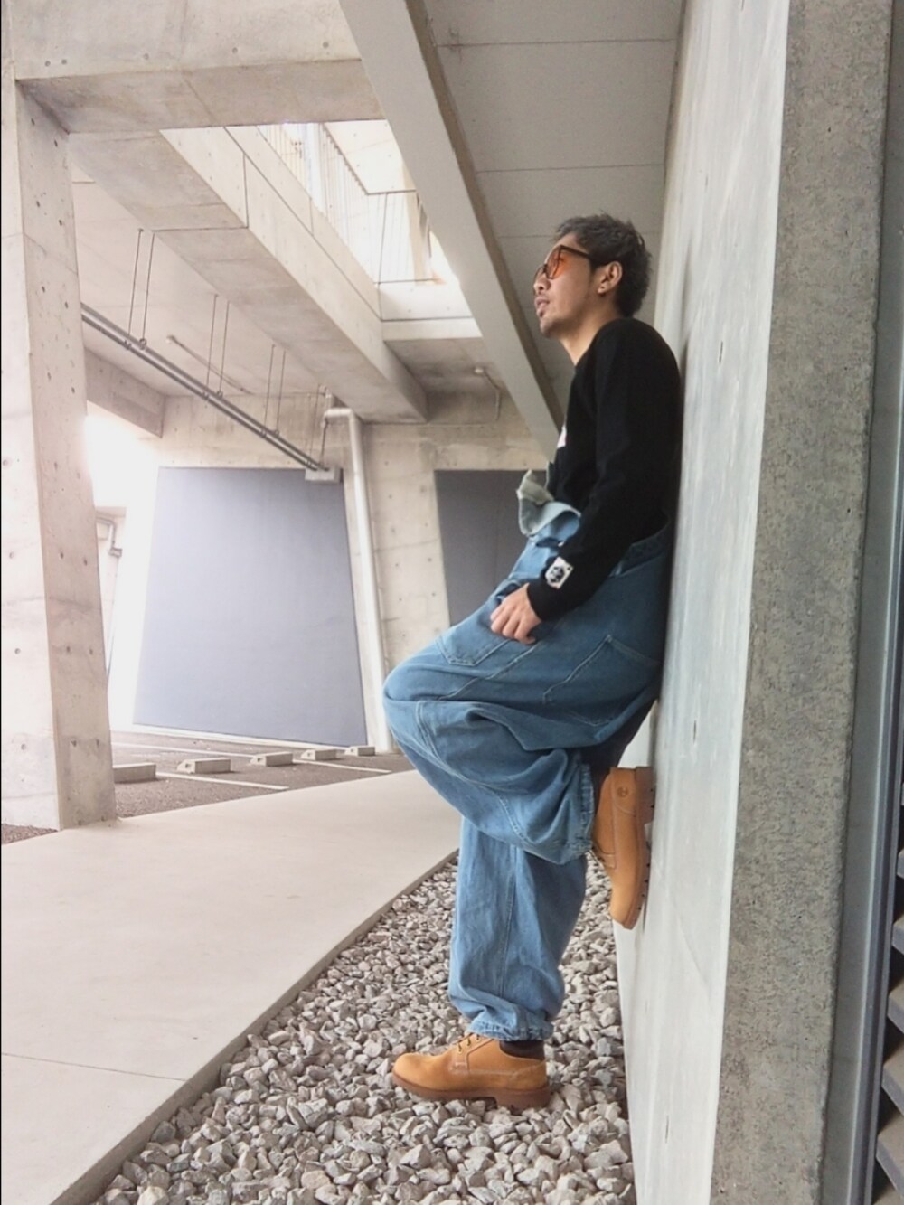 ブラック系のTシャツ/カットソー、ブルー系のサロペット/オーバーオール、イエロー系のブーツを着用したメンズの春コーディネートの2枚目の写真