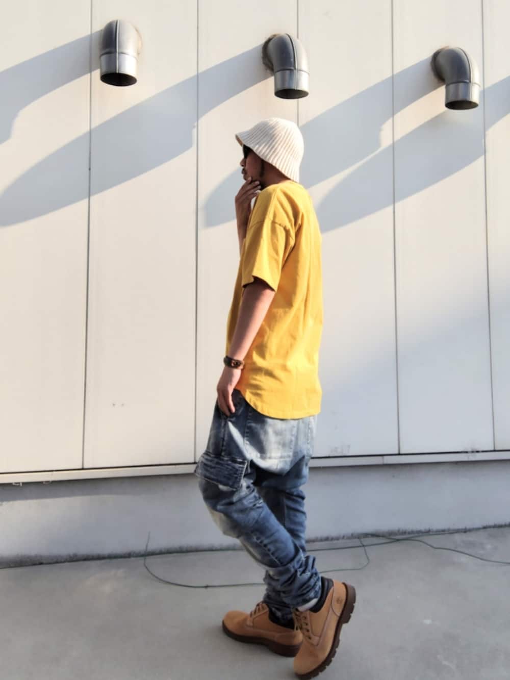 イエロー系のTシャツ/カットソー、ブルー系のデニムパンツ、イエロー系のブーツを着用したメンズの夏コーディネートの2枚目の写真
