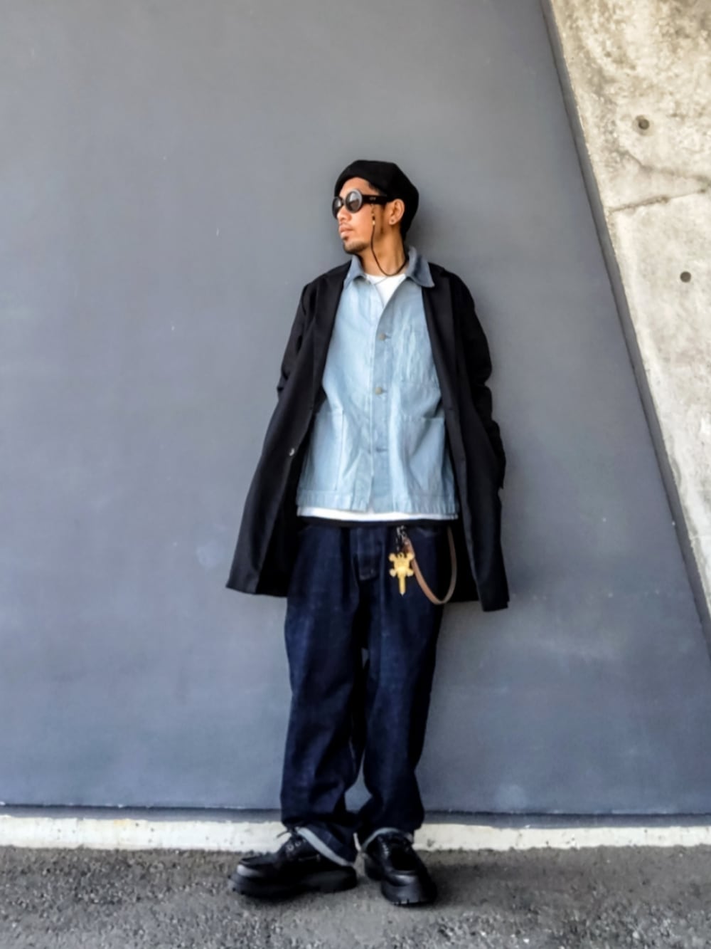 ブラック系のチェスターコート、ブルー系のデニムジャケット、ブルー系のデニムパンツを着用したメンズの春コーディネートの2枚目の写真