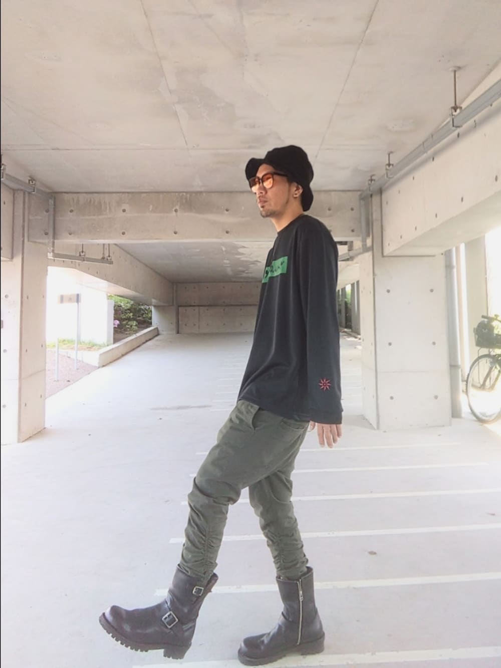 ブラック系のTシャツ/カットソー、グリーン系のパンツ、ブラック系のブーツを着用したメンズの春コーディネートの2枚目の写真