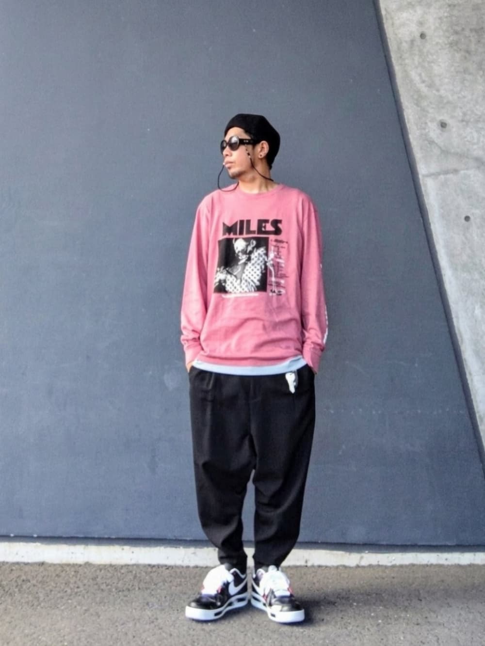 ピンク系のTシャツ/カットソー、ブラック系のスラックス、ブラック系のスニーカーを着用したメンズの秋コーディネートの2枚目の写真